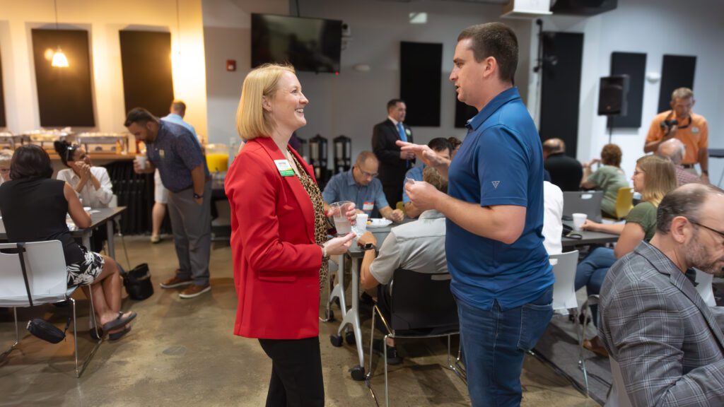 Image of 2 people networking with a group in the background